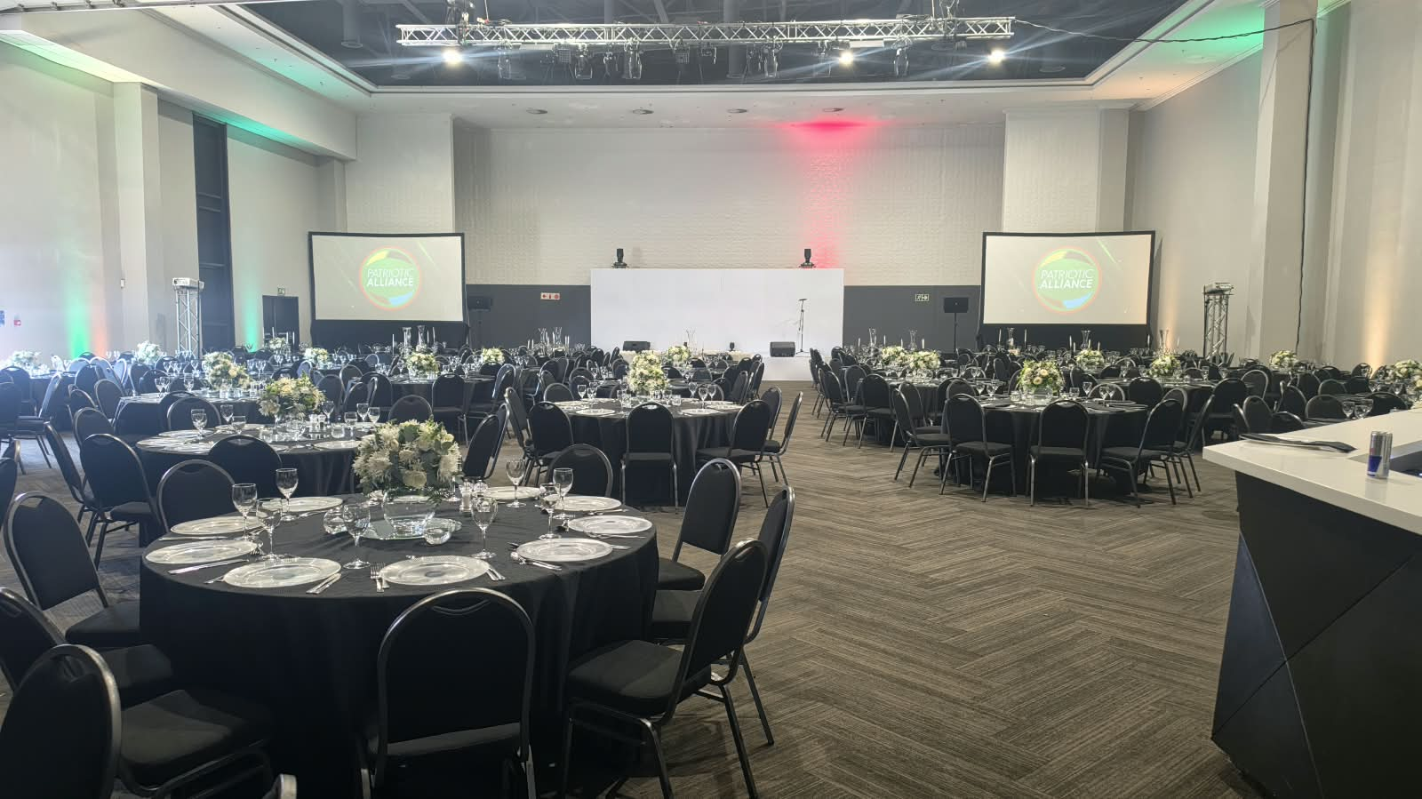 Conference banquet hall with round tables, staging and dual projection screens